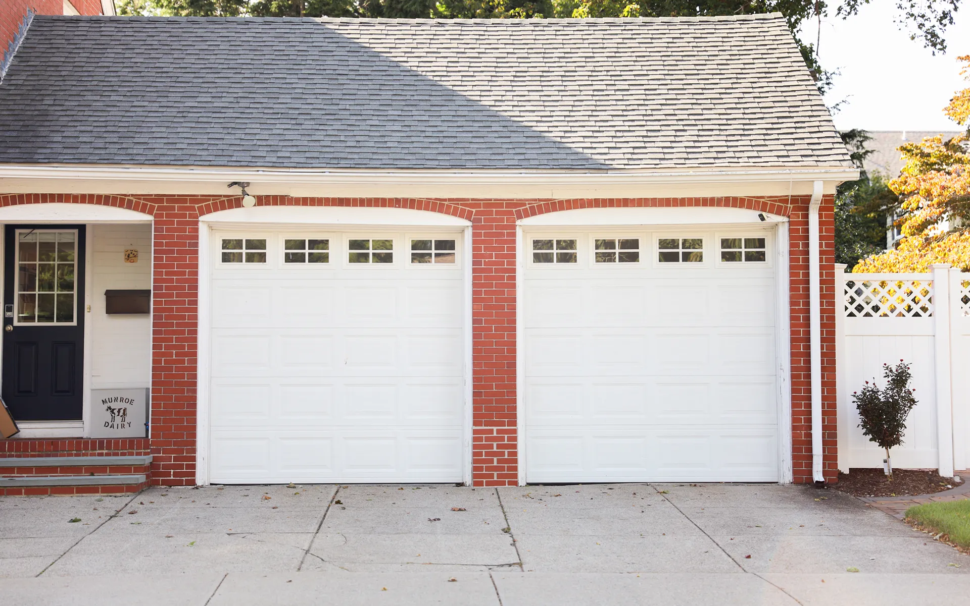 Suburban house with a white garage door nestled in a green garden epitomizing home security